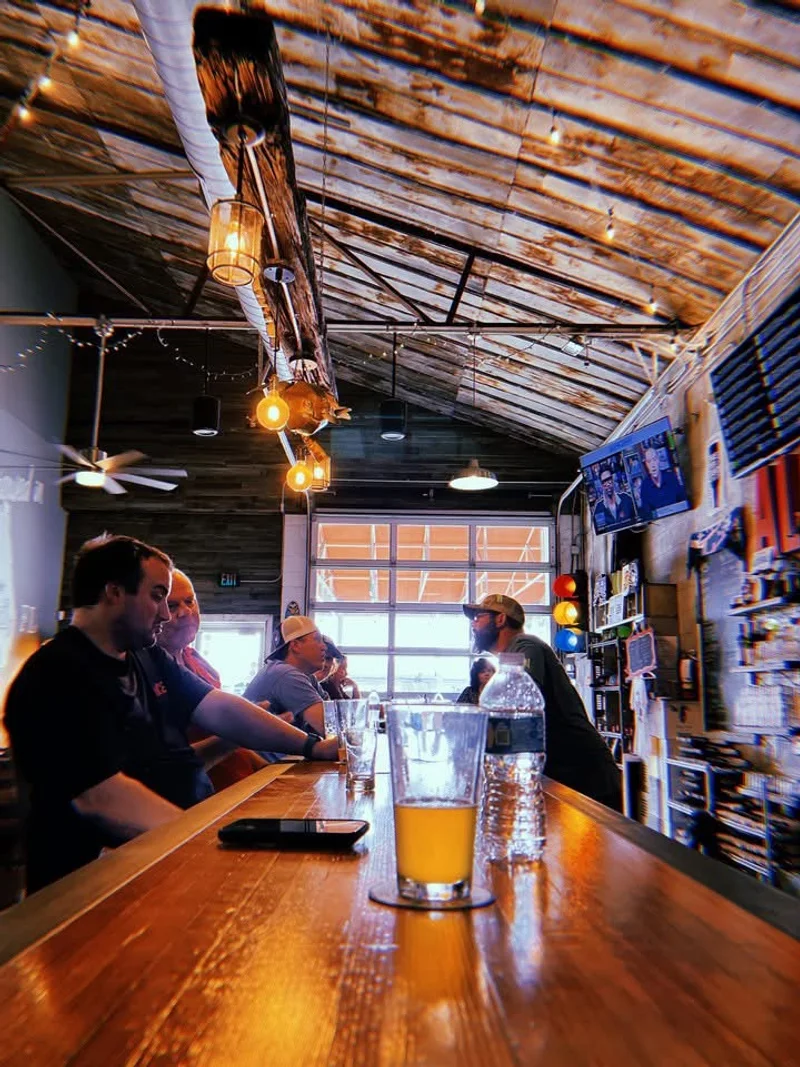 Looking down the bowling alley bar at Swan Brewing, pint of beer in the foreground, roll-up door open to the patio behind