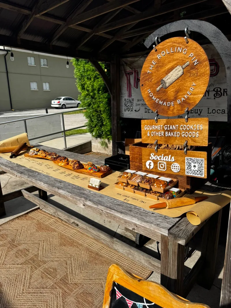 The Rolling Pin bakery setup under the Swan Brewing gazebo, with baked goods displayed on the picnic table and Swan Brewing signage behind